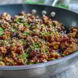 A plated serving of Korean-Style Ground Turkey, garnished with toasted sesame seeds and chives over fluffy white rice.