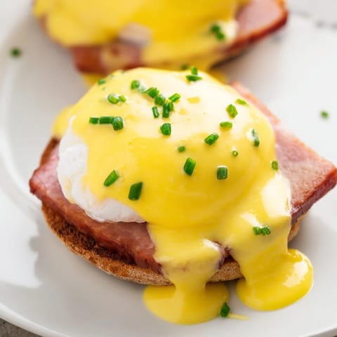 Classic brunch Eggs Benedict with runny poached eggs, crisp bacon, and rich hollandaise sauce.
