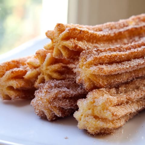 Golden, crispy churros coated in cinnamon sugar and drizzled with rich chocolate sauce, ready to serve.