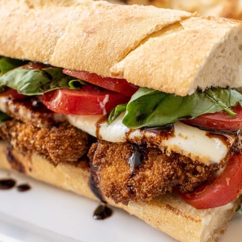 Fresh basil and ripe tomato slices complement the crunchy panko-crusted chicken cutlet, drizzled with balsamic glaze on a warm ciabatta roll.  