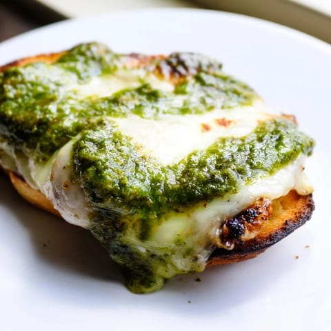 Close-up of a Pesto Chicken Melt, highlighting golden grilled chicken and vibrant basil pesto.  