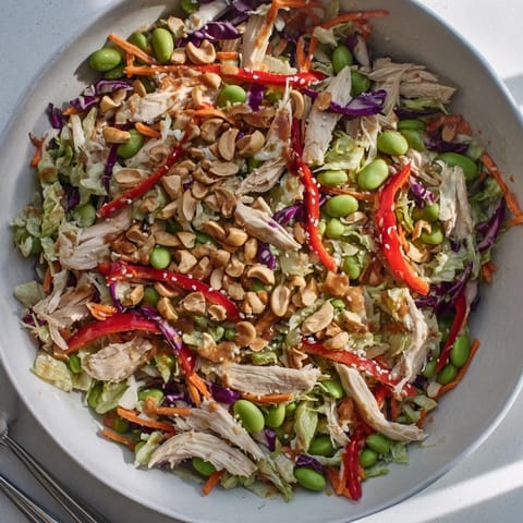 A close-up of Edamame Crunch Chicken Salad shows vibrant veggies and cashews tossed in a zesty ginger dressing, ideal for a healthy lunch or light dinner.