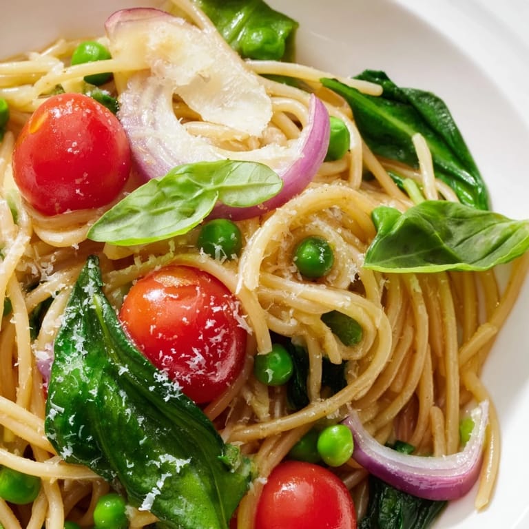 The finished Spring Veggie One-Pot Spaghetti served in a rustic ceramic bowl, showcasing the colorful mix of spinach, peas, and tomatoes, perfect for a quick vegetarian dinner.