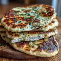 Golden-brown The Best Easy Garlic Naan Bread fresh from the skillet, glistening with melted butter and flecked with minced garlic.